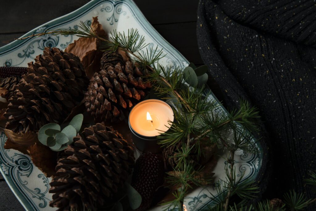 A nature altar decorated with pine cones, evergreen pine needles and a candle