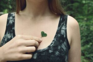 What is Nature Connection? Woman holding clover leaf to her heart.